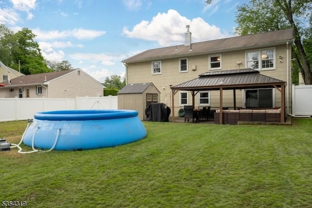 back of house featuring an outdoor living space, a fenced in pool, a shed, a fenced backyard, and a yard