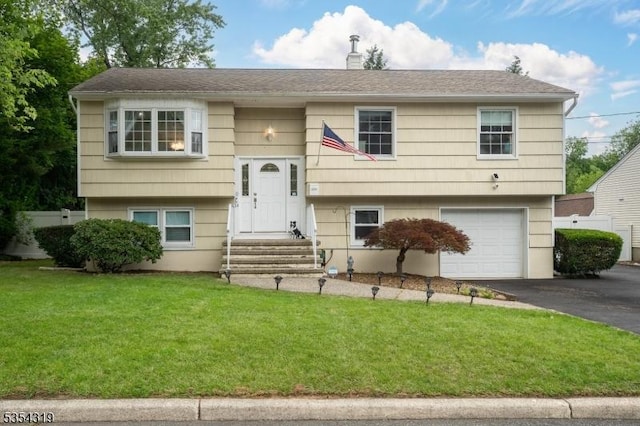 raised ranch with a garage, a front yard, and aphalt driveway