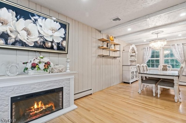interior space featuring a fireplace, wood finished floors, beamed ceiling, a baseboard heating unit, and an inviting chandelier