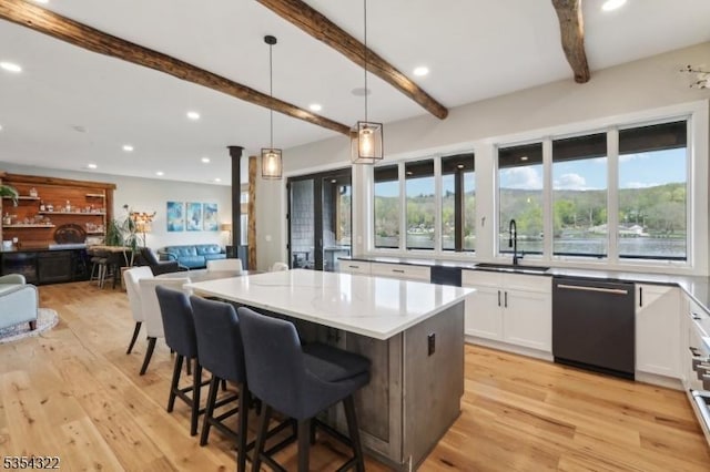 kitchen with beam ceiling, dishwashing machine, plenty of natural light, white cabinetry, and a sink