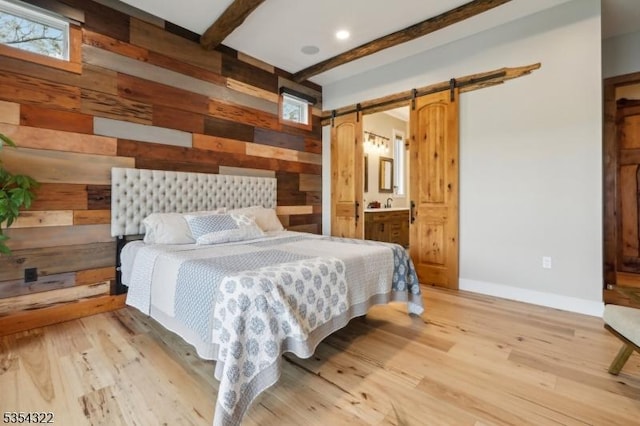 bedroom featuring a barn door, light wood finished floors, beam ceiling, and wooden walls