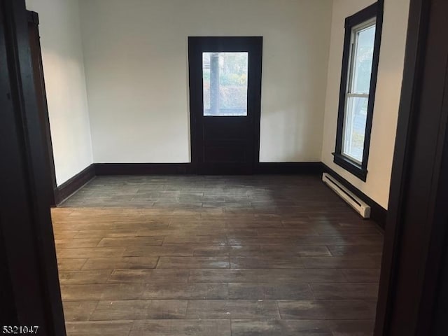 spare room with baseboards, a baseboard heating unit, and wood finished floors