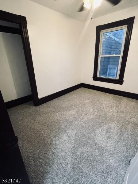 carpeted spare room featuring ceiling fan and baseboards