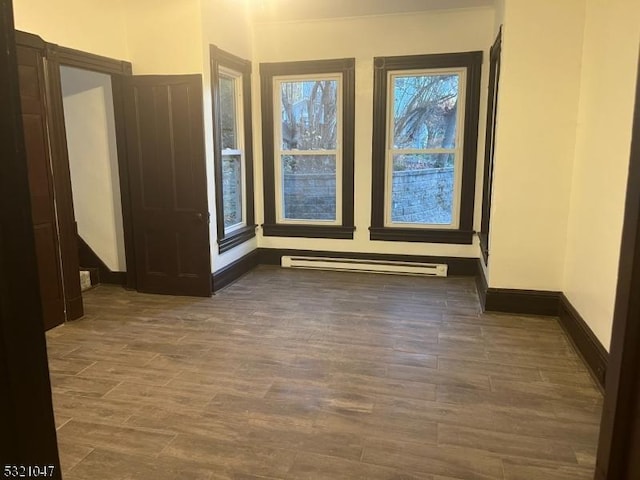 empty room featuring baseboards, wood finished floors, and baseboard heating