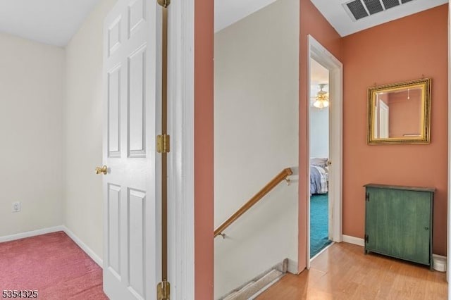 hall with baseboards, an upstairs landing, carpet, and visible vents