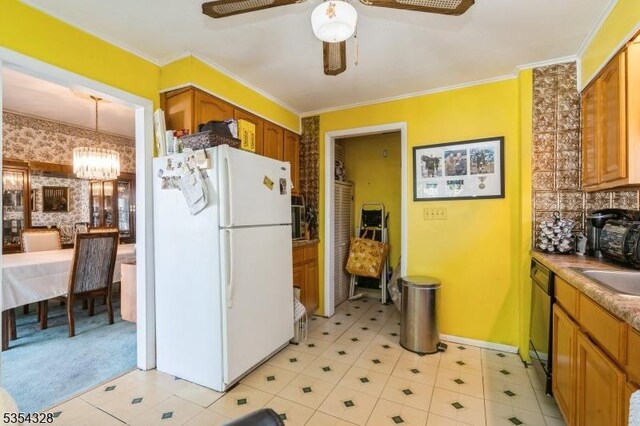 kitchen with brown cabinetry, ceiling fan with notable chandelier, freestanding refrigerator, dishwasher, and crown molding