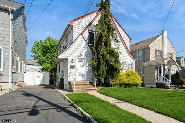 bungalow-style home featuring entry steps, a front lawn, and a gate