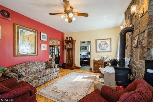 living room featuring a wood stove, visible vents, and a ceiling fan