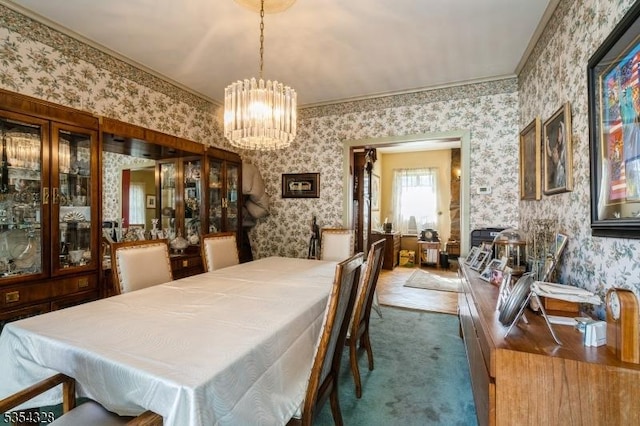 carpeted dining room featuring wallpapered walls, a chandelier, and crown molding