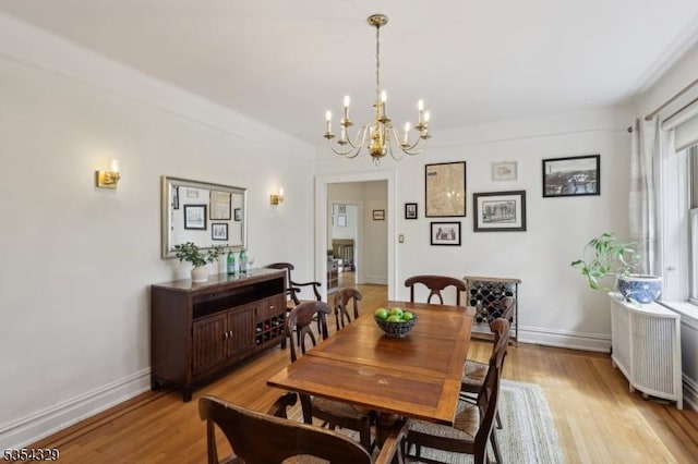 dining room with light wood-style floors, a chandelier, and baseboards
