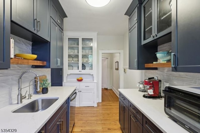 kitchen with a sink, light countertops, open shelves, and dishwasher