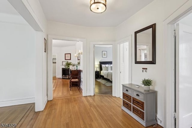 hallway with light wood-type flooring and baseboards