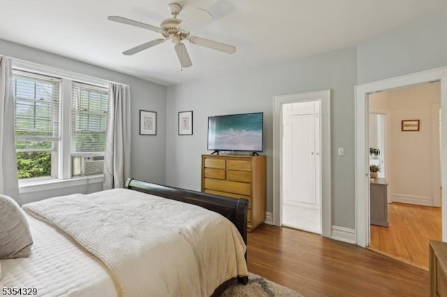 bedroom featuring wood finished floors, ceiling fan, cooling unit, and baseboards