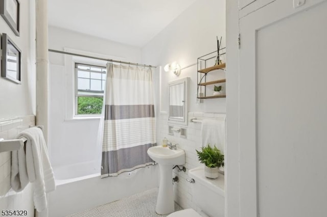 bathroom featuring tile walls, toilet, tile patterned floors, shower / bathtub combination with curtain, and wainscoting