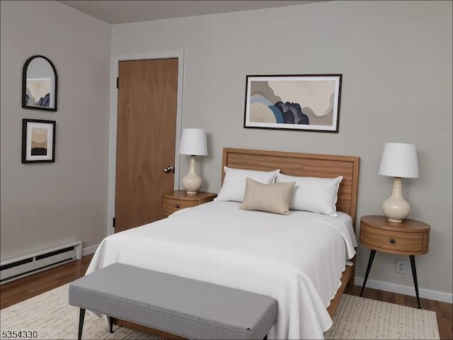 bedroom with baseboards, baseboard heating, and wood finished floors