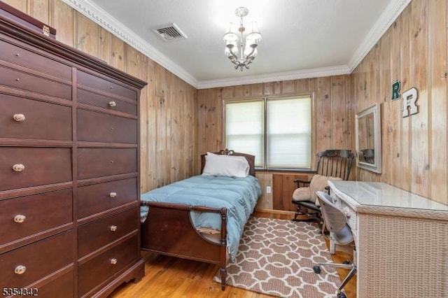 bedroom with visible vents, a notable chandelier, wooden walls, ornamental molding, and light wood-style flooring
