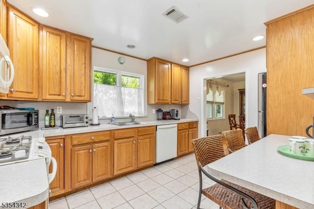 kitchen with white dishwasher, a sink, stainless steel microwave, light tile patterned floors, and visible vents