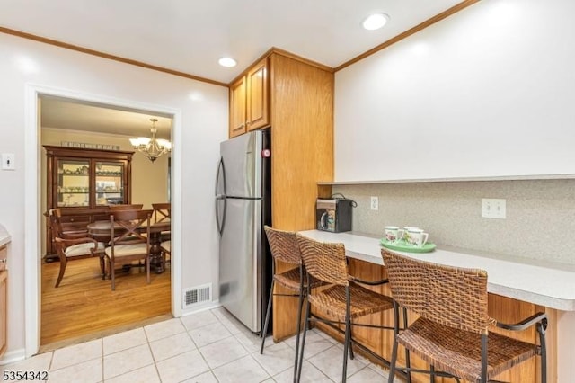 kitchen with light countertops, freestanding refrigerator, and ornamental molding