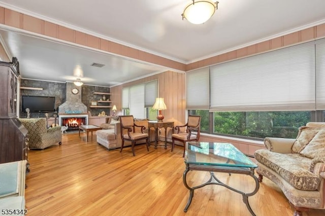 interior space featuring ornamental molding, a fireplace, wood finished floors, and visible vents