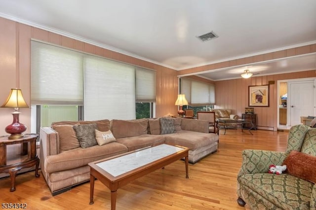 living room with crown molding, light wood-style flooring, and visible vents
