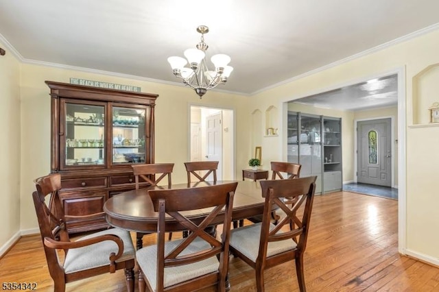 dining room featuring an inviting chandelier, light wood-style flooring, crown molding, and baseboards