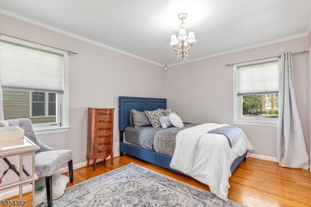 bedroom with baseboards, a notable chandelier, ornamental molding, and wood finished floors