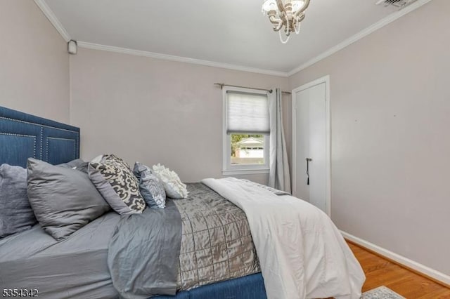 bedroom featuring crown molding, baseboards, an inviting chandelier, and wood finished floors