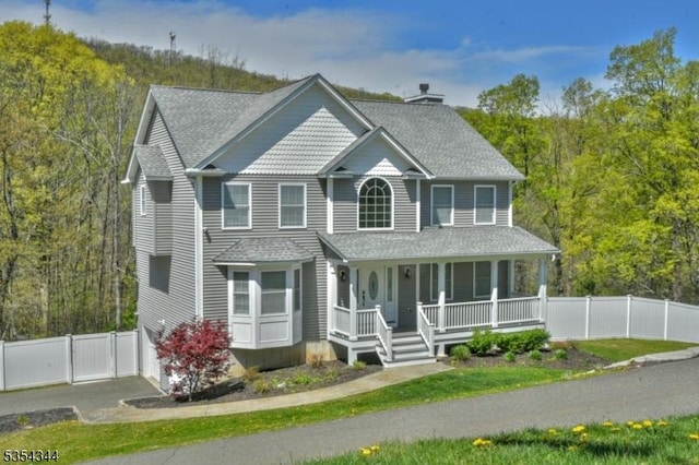 view of front of property featuring a porch, a chimney, a garage, fence, and a shingled roof