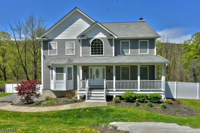 view of front of home with fence, a chimney, a porch, and a front yard