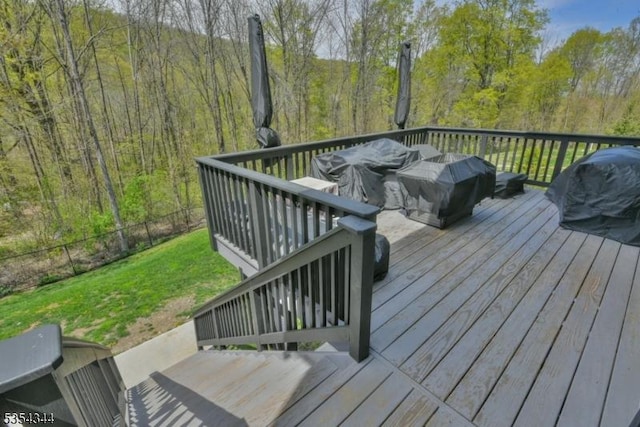 wooden terrace with fence, a view of trees, and a yard
