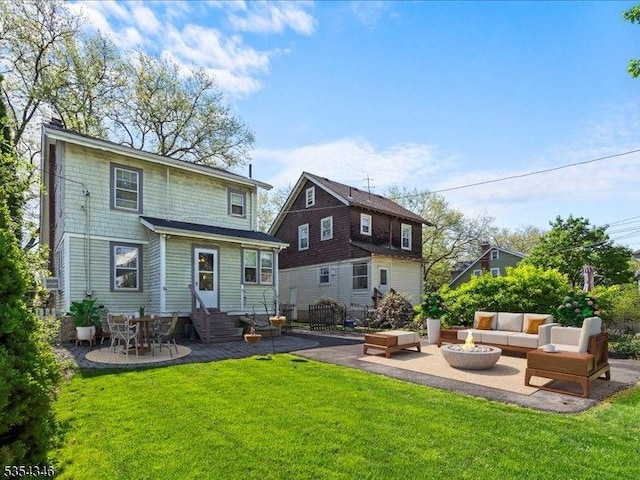 rear view of property featuring entry steps, an outdoor living space with a fire pit, a yard, and a patio area