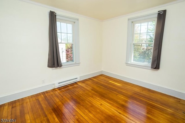 spare room with baseboards, ornamental molding, a baseboard heating unit, and hardwood / wood-style floors