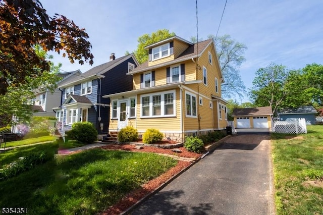 american foursquare style home with a garage, an outdoor structure, entry steps, and a front lawn