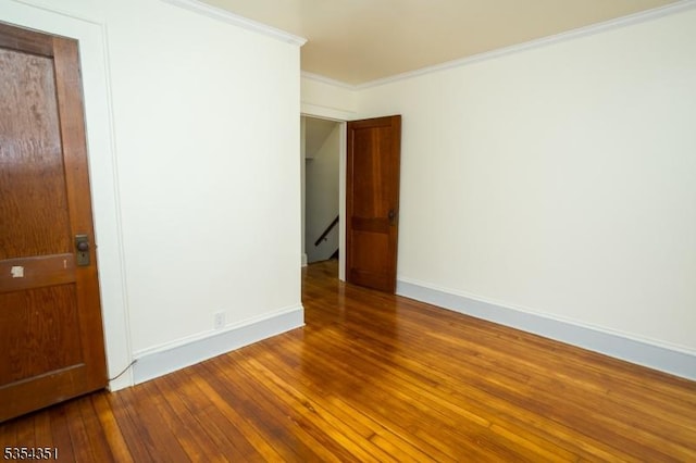 spare room with baseboards, ornamental molding, and wood finished floors