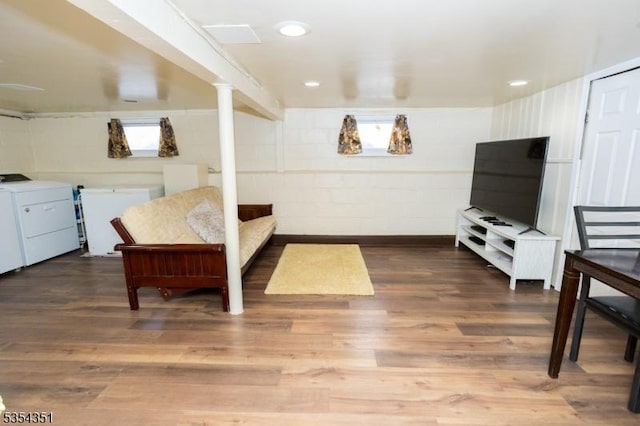 interior space with concrete block wall, wood finished floors, and washing machine and clothes dryer