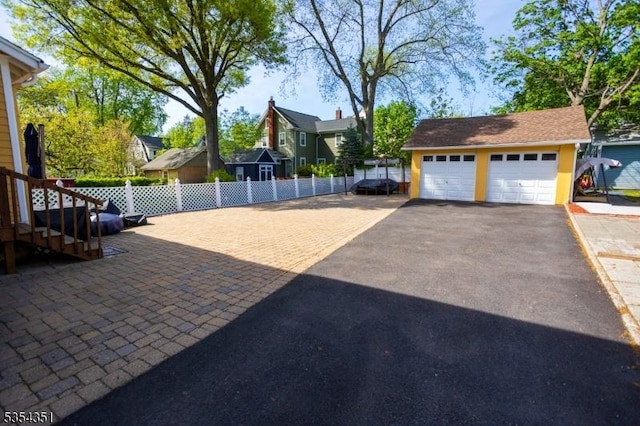 exterior space featuring a detached garage, fence, a residential view, and an outdoor structure