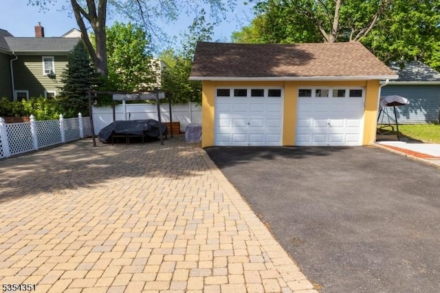 garage featuring fence and driveway