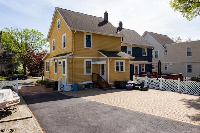 back of property featuring fence, a chimney, and entry steps