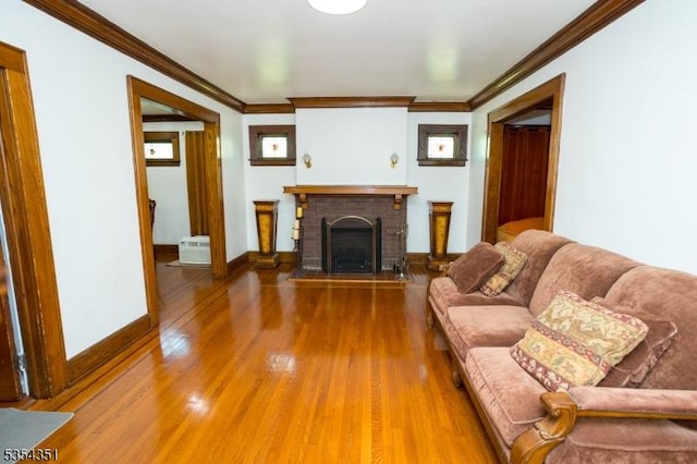 living room with crown molding, baseboards, wood finished floors, and a fireplace