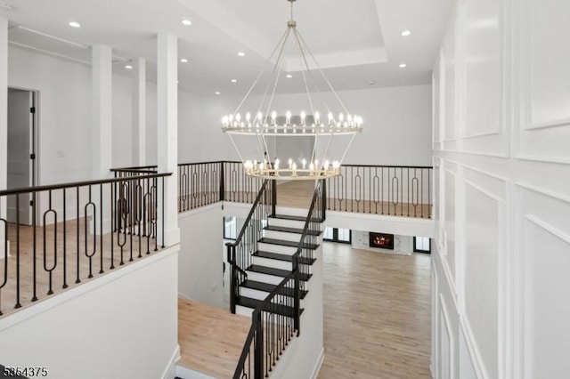 stairway featuring recessed lighting, wood finished floors, and a notable chandelier