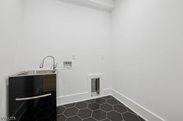 washroom featuring dark tile patterned floors, laundry area, a sink, baseboards, and hookup for a washing machine