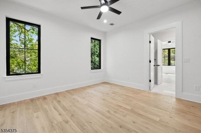 empty room featuring a ceiling fan, baseboards, visible vents, and light wood finished floors