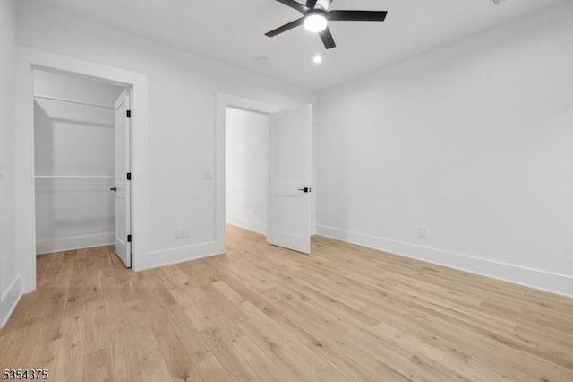 unfurnished bedroom with light wood-style floors, baseboards, ceiling fan, and a spacious closet