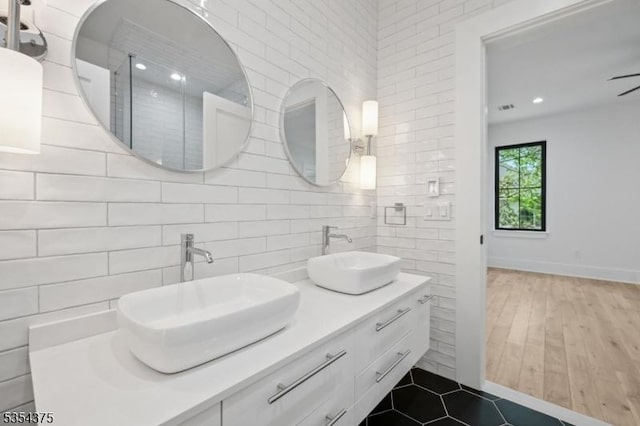 bathroom featuring double vanity, a sink, decorative backsplash, and tile walls