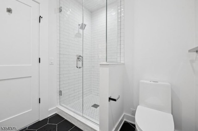 bathroom featuring baseboards, tile patterned flooring, a stall shower, and toilet