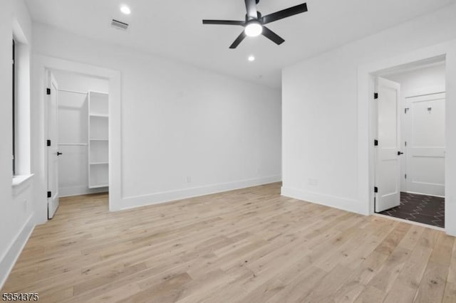unfurnished bedroom featuring ceiling fan, baseboards, a spacious closet, light wood-style floors, and recessed lighting