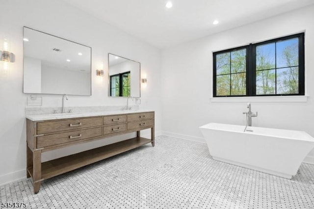 bathroom featuring a freestanding bath, baseboards, recessed lighting, and double vanity