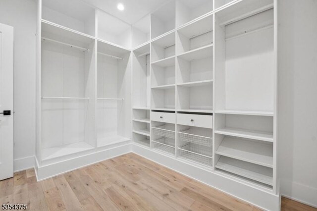 walk in closet with wood finished floors