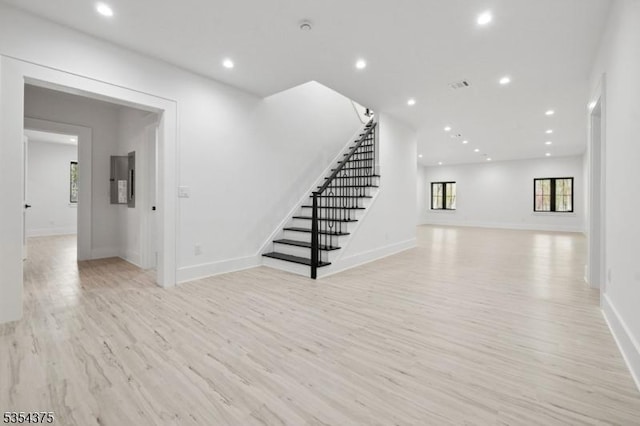 unfurnished living room featuring light wood-type flooring, recessed lighting, stairs, and baseboards