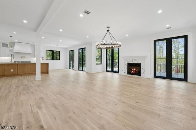 unfurnished living room featuring recessed lighting, visible vents, a high end fireplace, and light wood-type flooring